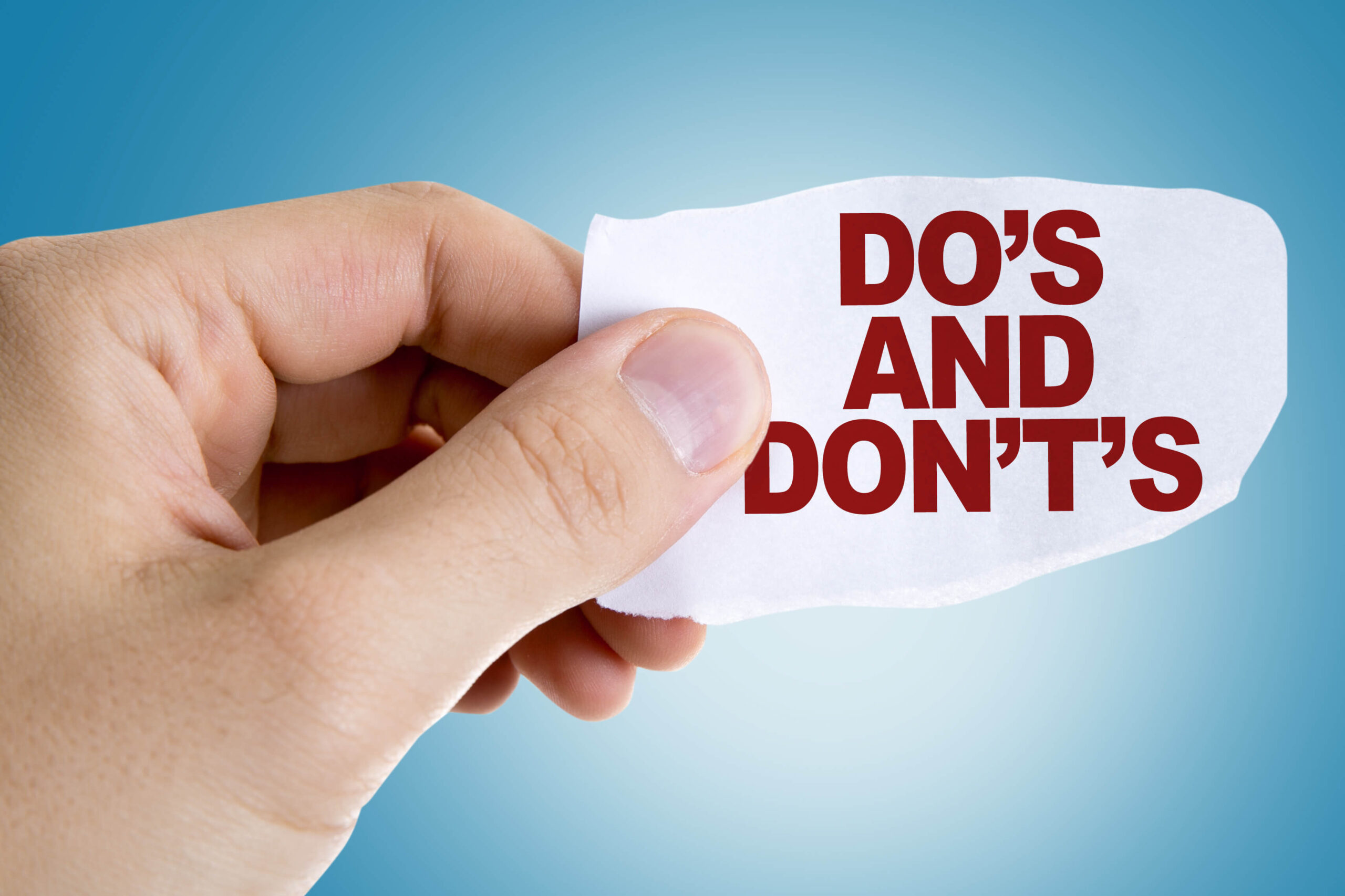 A person holding up a piece of paper with the words " do 's and don 't s ".